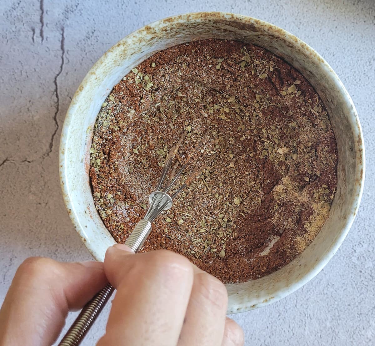 hand whisking spices in a bowl