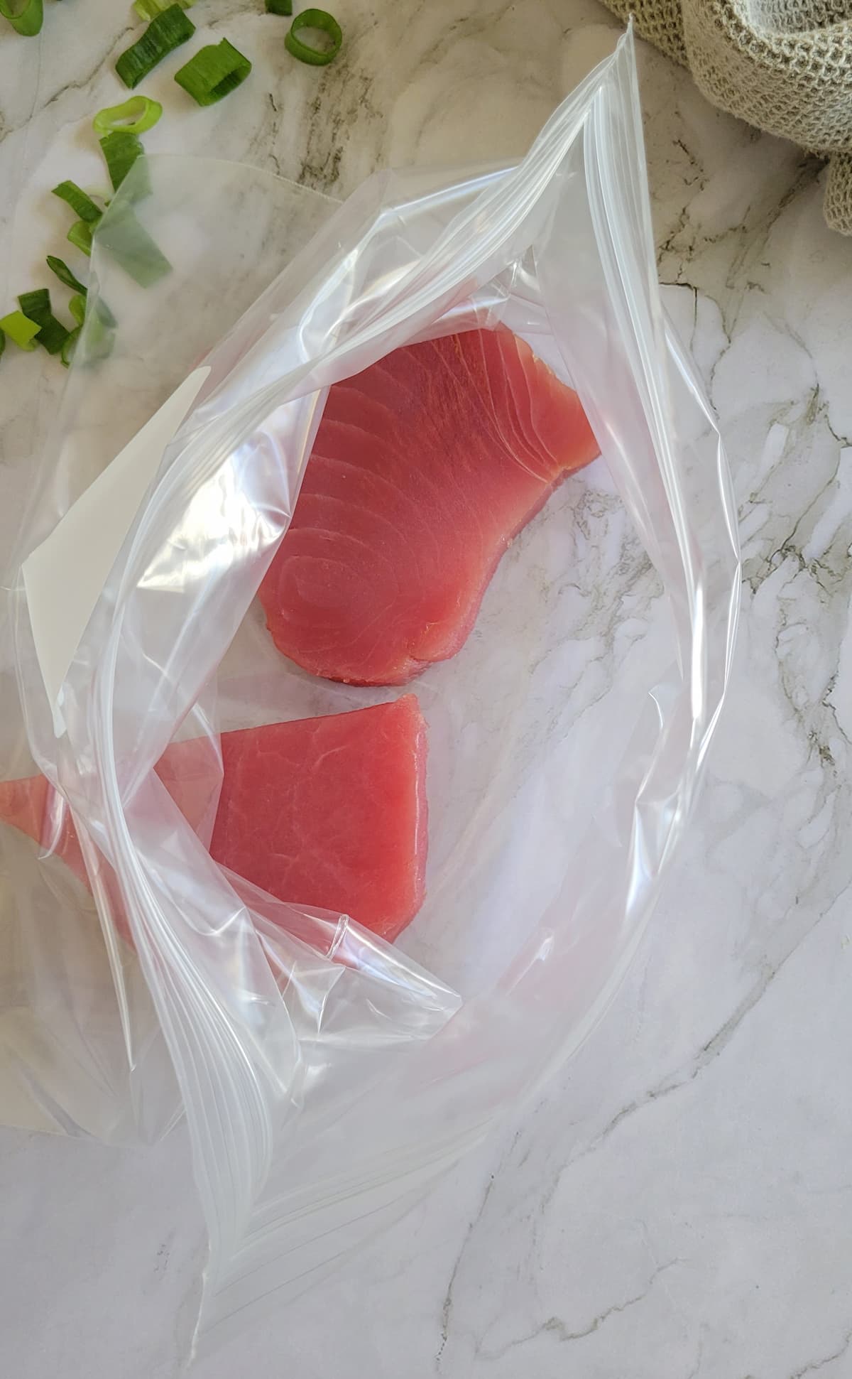 two raw tuna steaks in a ziploc bag