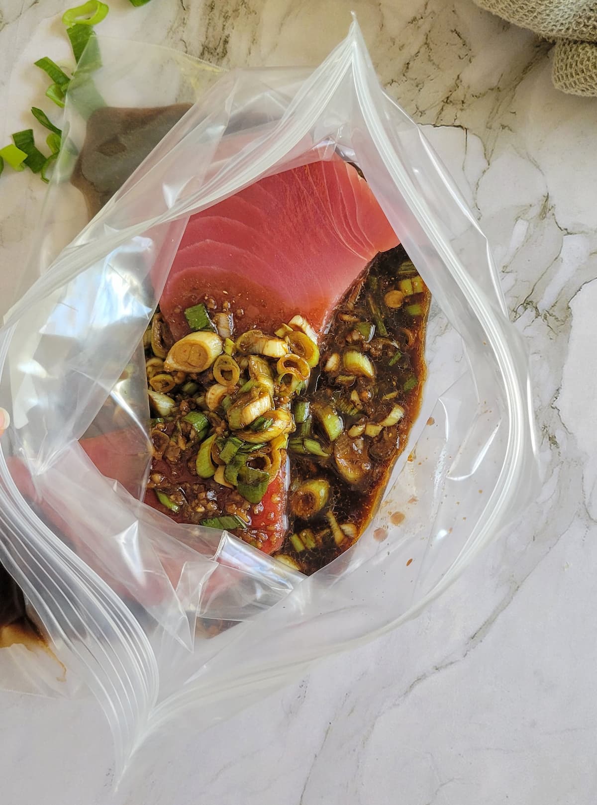 two raw tuna steaks in a ziploc bag with a marinade over top
