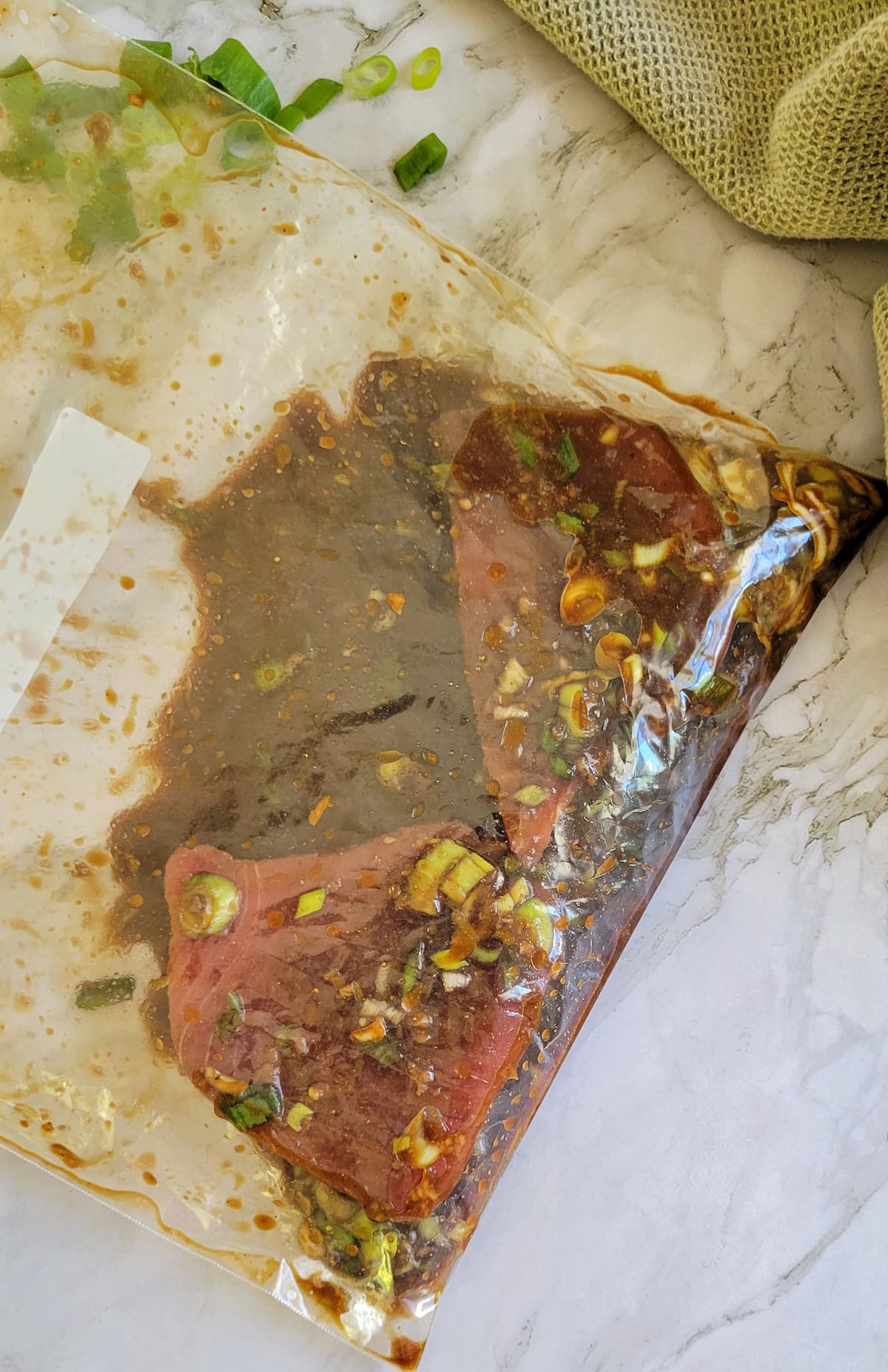 two raw tuna steaks marinating in a ziploc bag