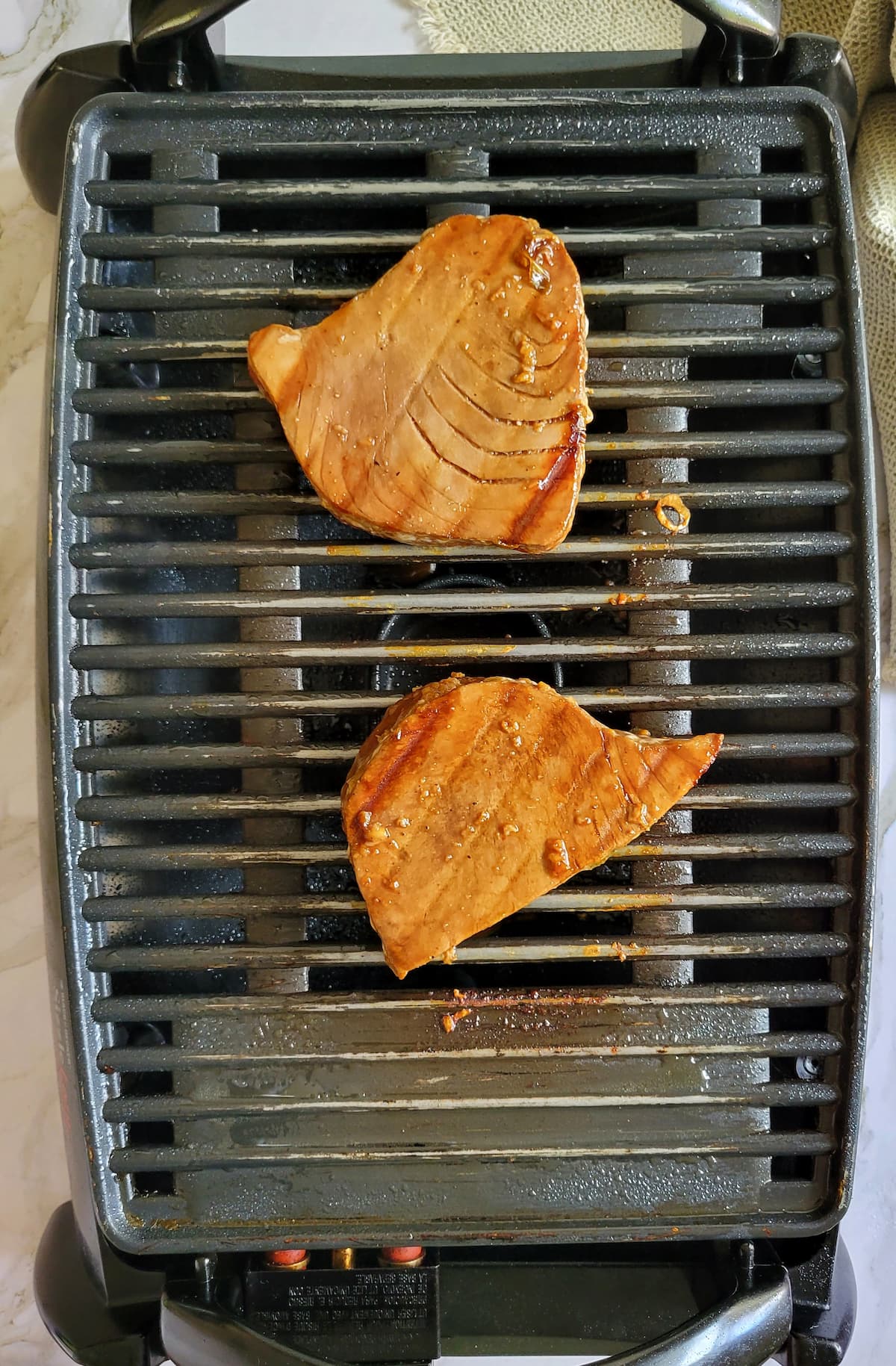 two tuna steaks grilling on a grill