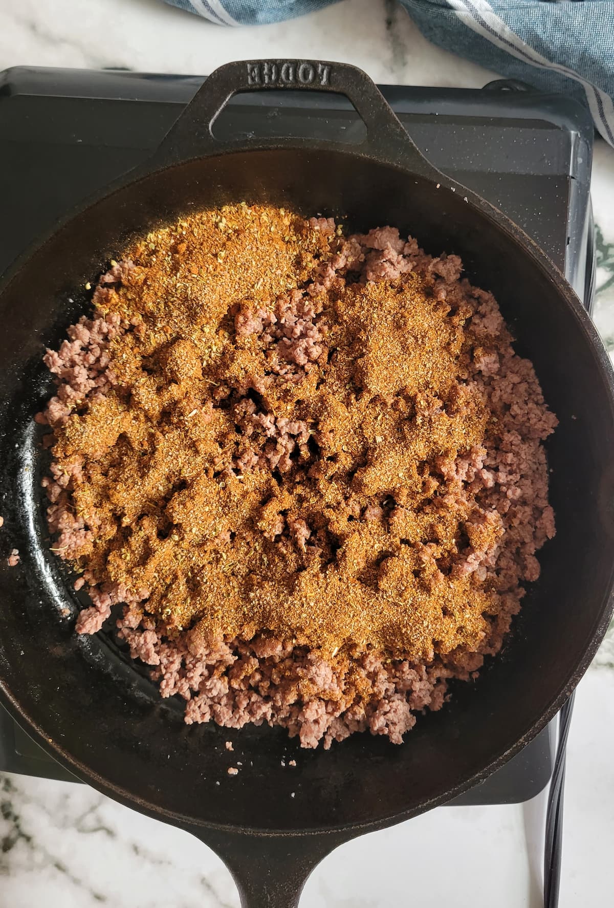 ground beef in a skillet with spices on top