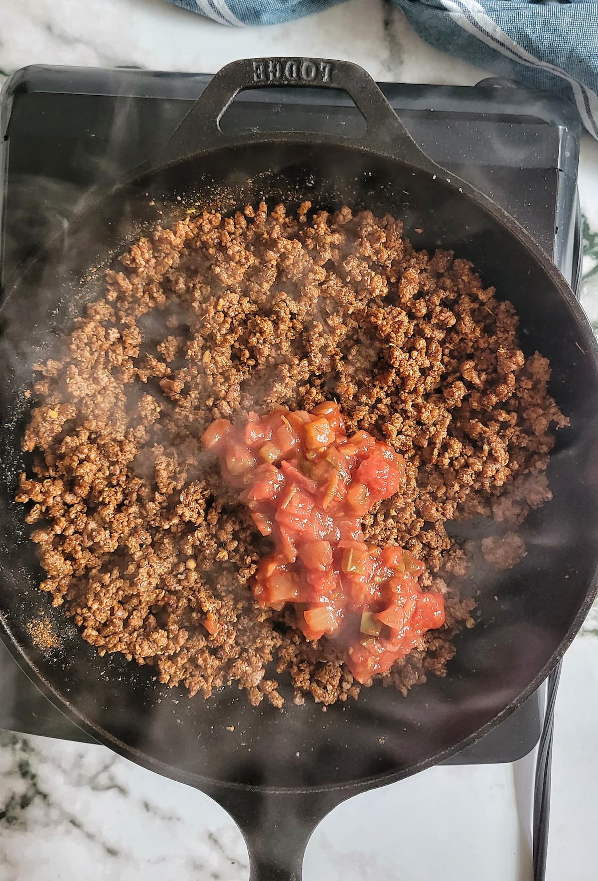 ground beef in a skillet with salsa on top