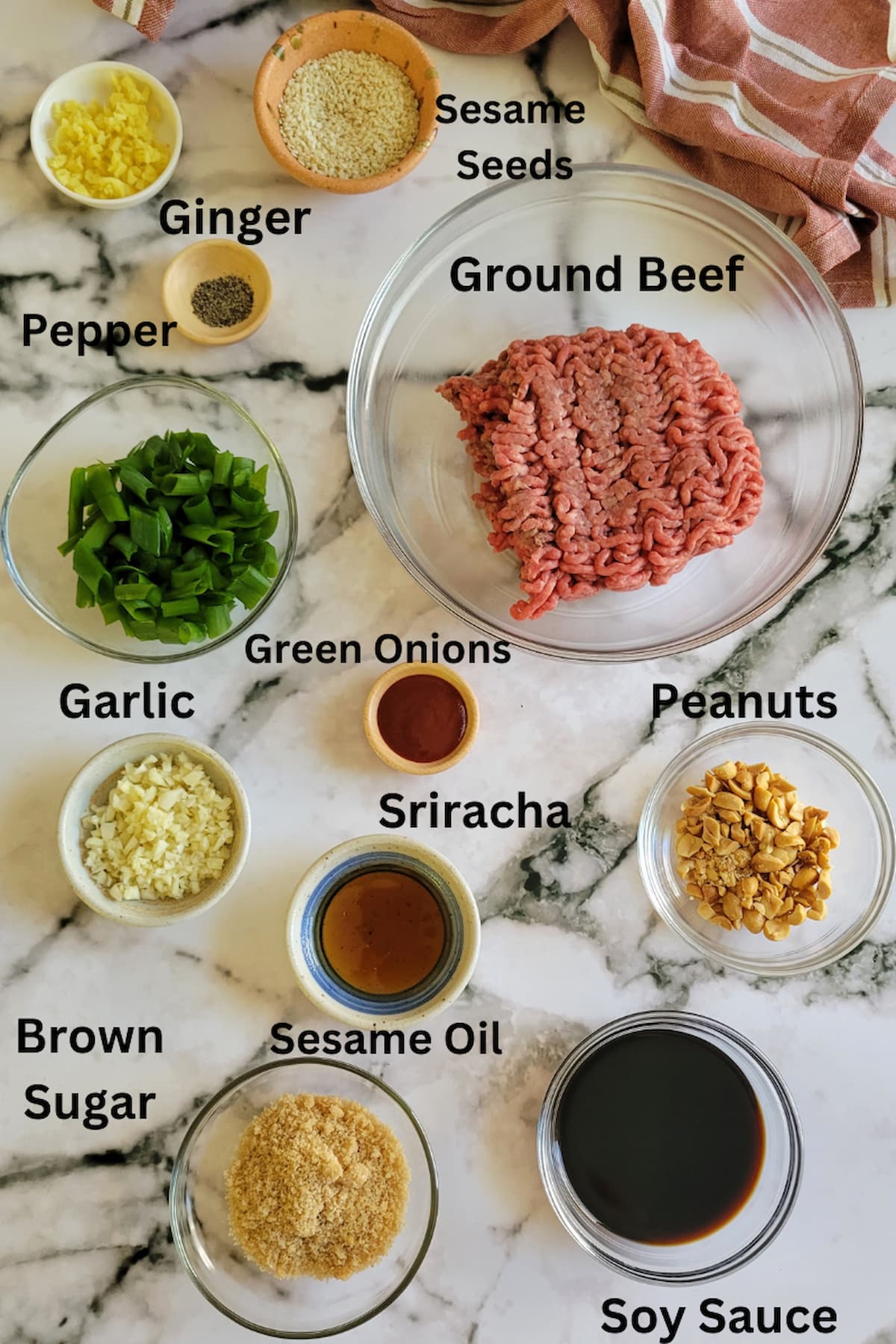 ingredients for ground beef with rice - ground beef, garlic, sesame seeds, pepper, ginger, green onions, brown sugar, sriracha, peanuts, soy sauce, sesame oil