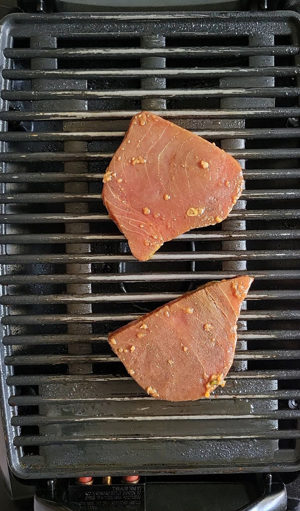 two tuna steaks grilling on a grill
