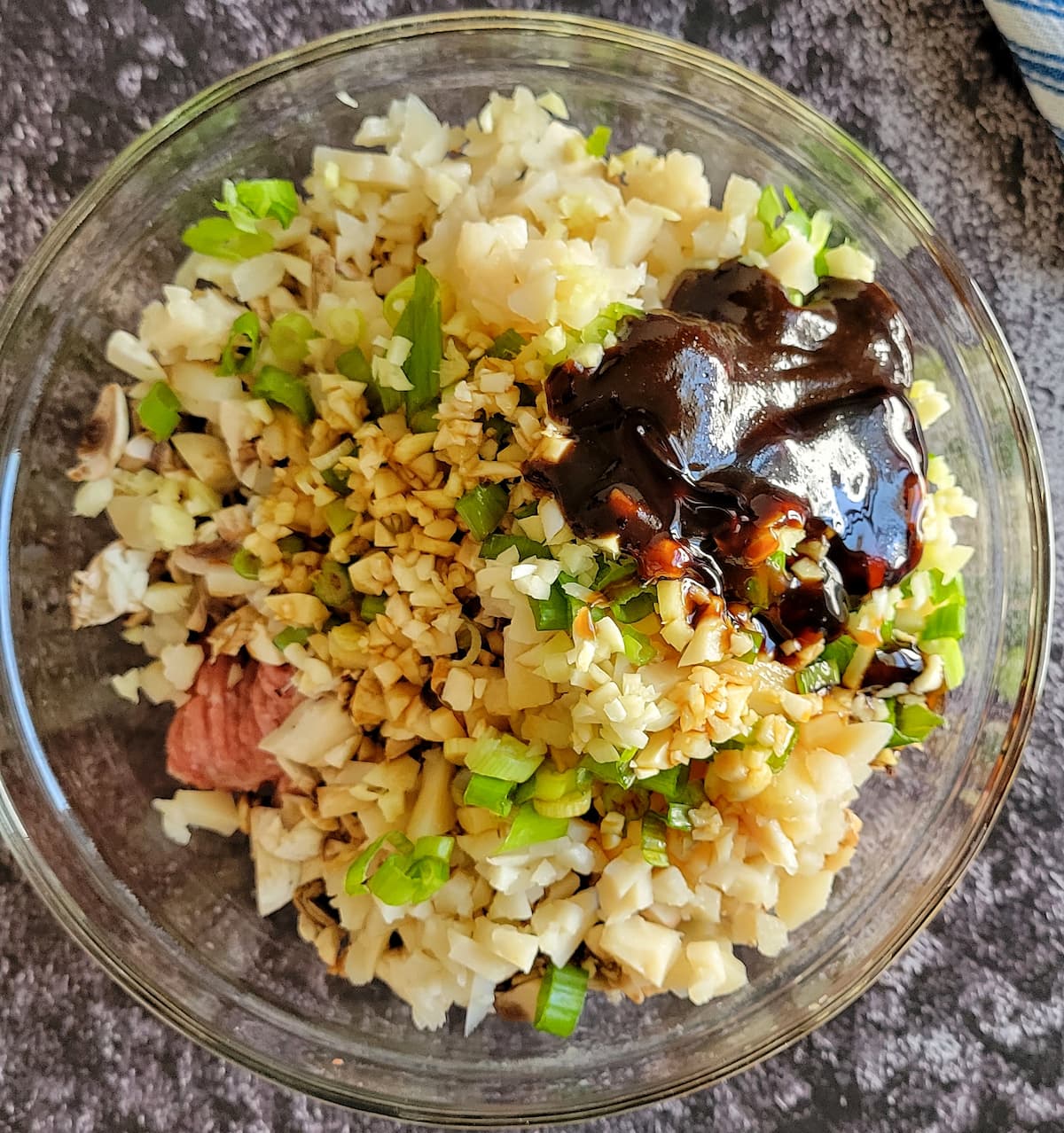 chopped ingredients unmixed in a bowl with a brown sauce