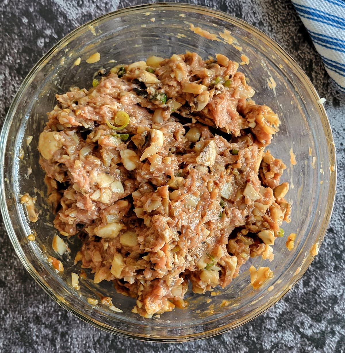 raw ground chicken mixed with chopped green onions and other ingredients in a bowl