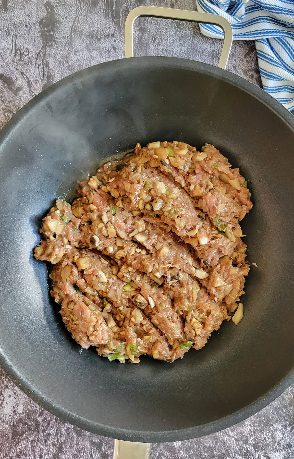raw minced ground chicken mixed with chopped mushrooms and green onions in a wok