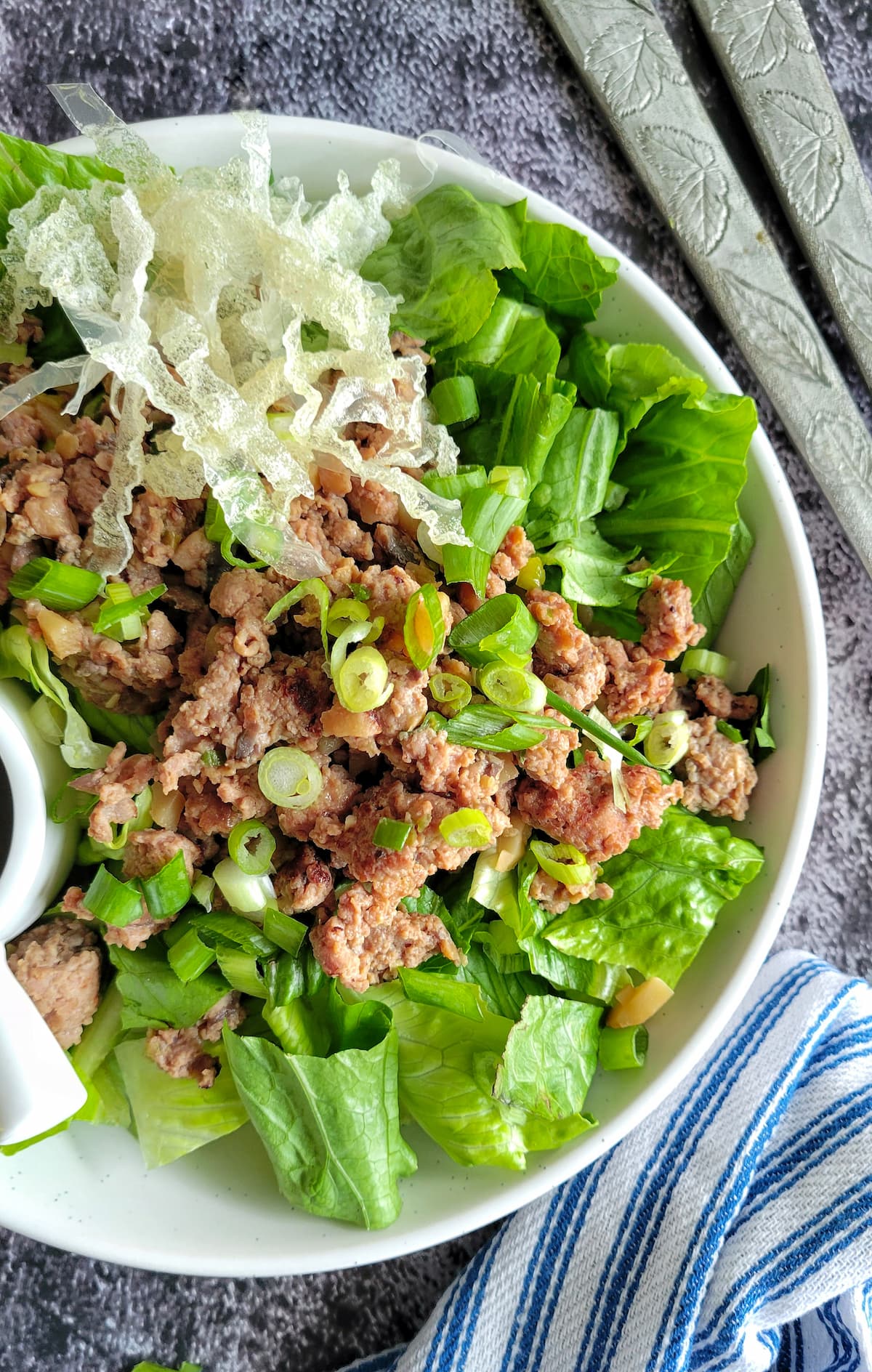 bowl of ground chicken salad with green onions and fried rice paper strips