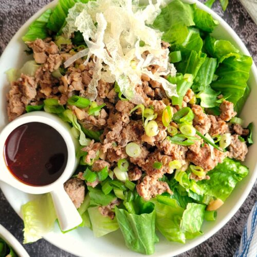 ground chicken salad in a bowl with a dark coloured dressing in a ramekin