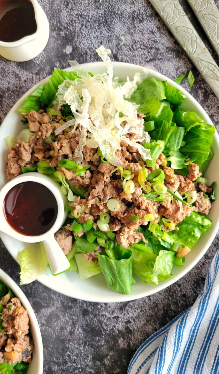 ground chicken salad in a bowl with a dark coloured dressing in a ramekin