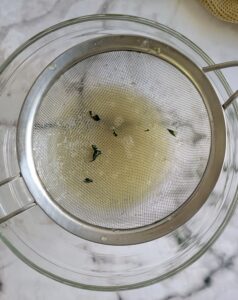 fine mesh strainer over a bowl with green liquid