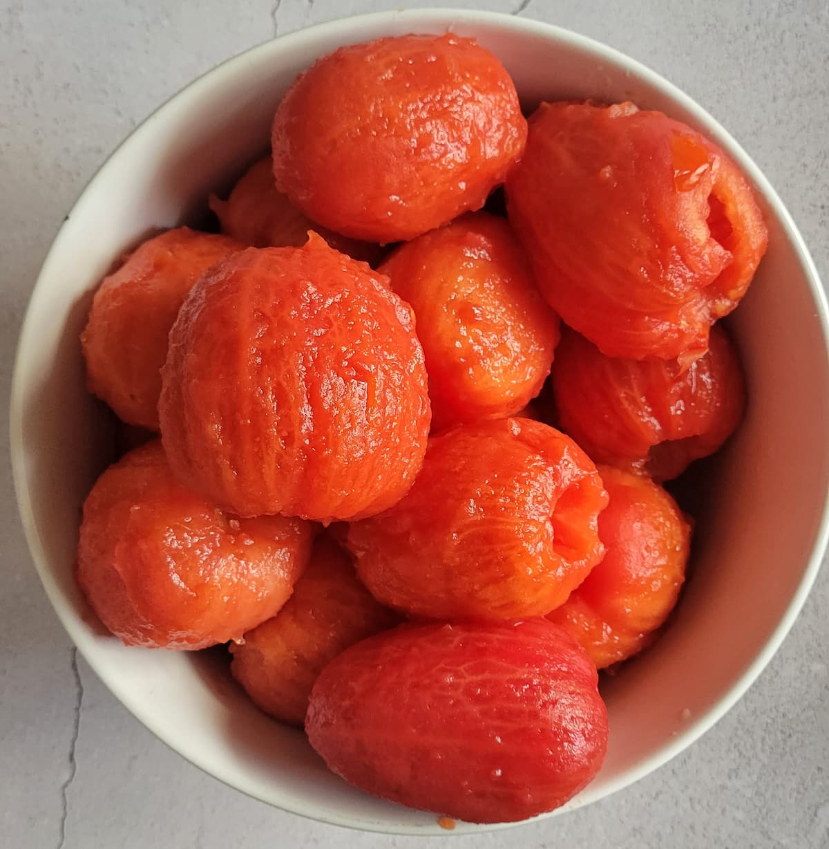 whole, peeled and cored tomatoes in a bowl