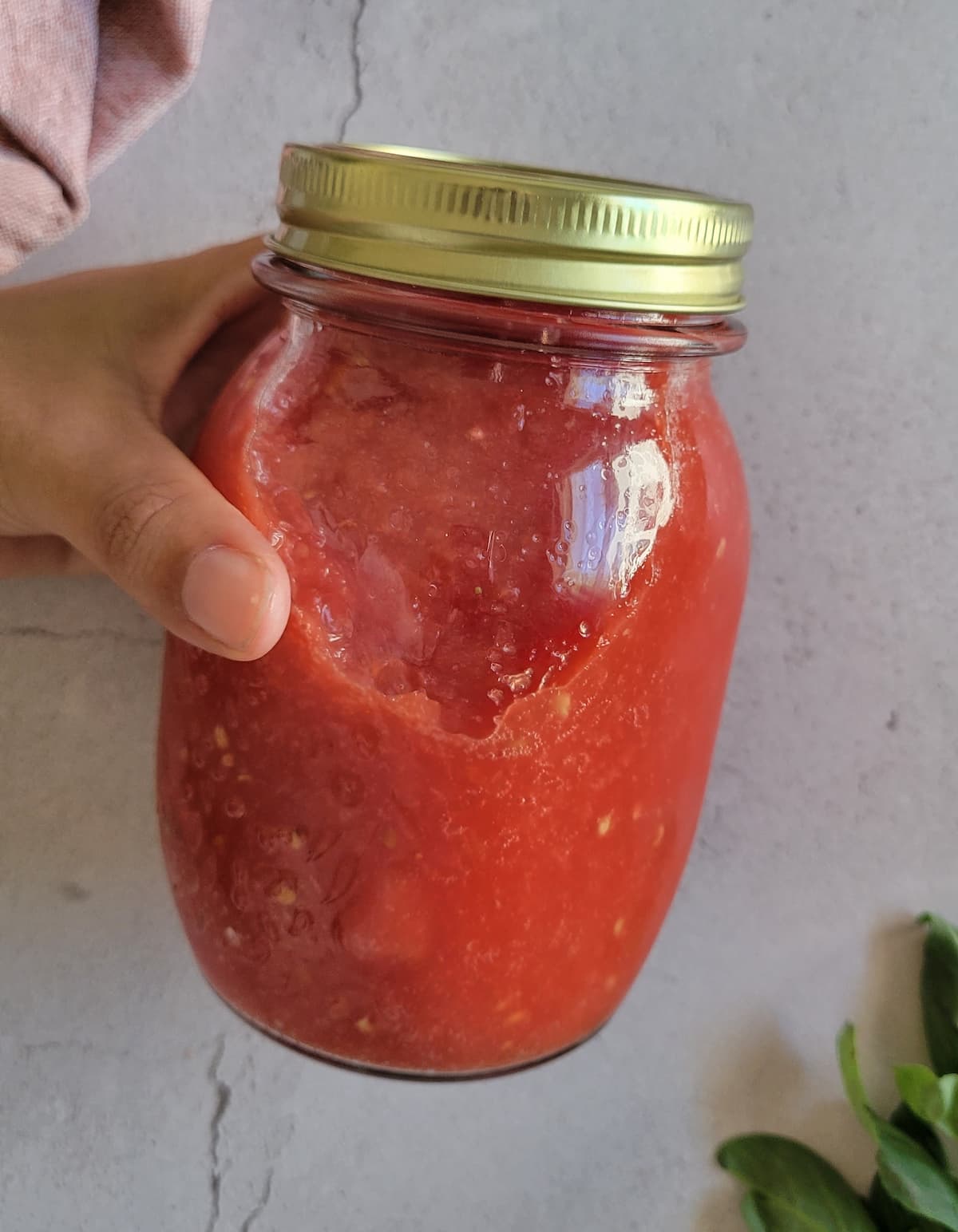 hand holding a jar of tomato sauce