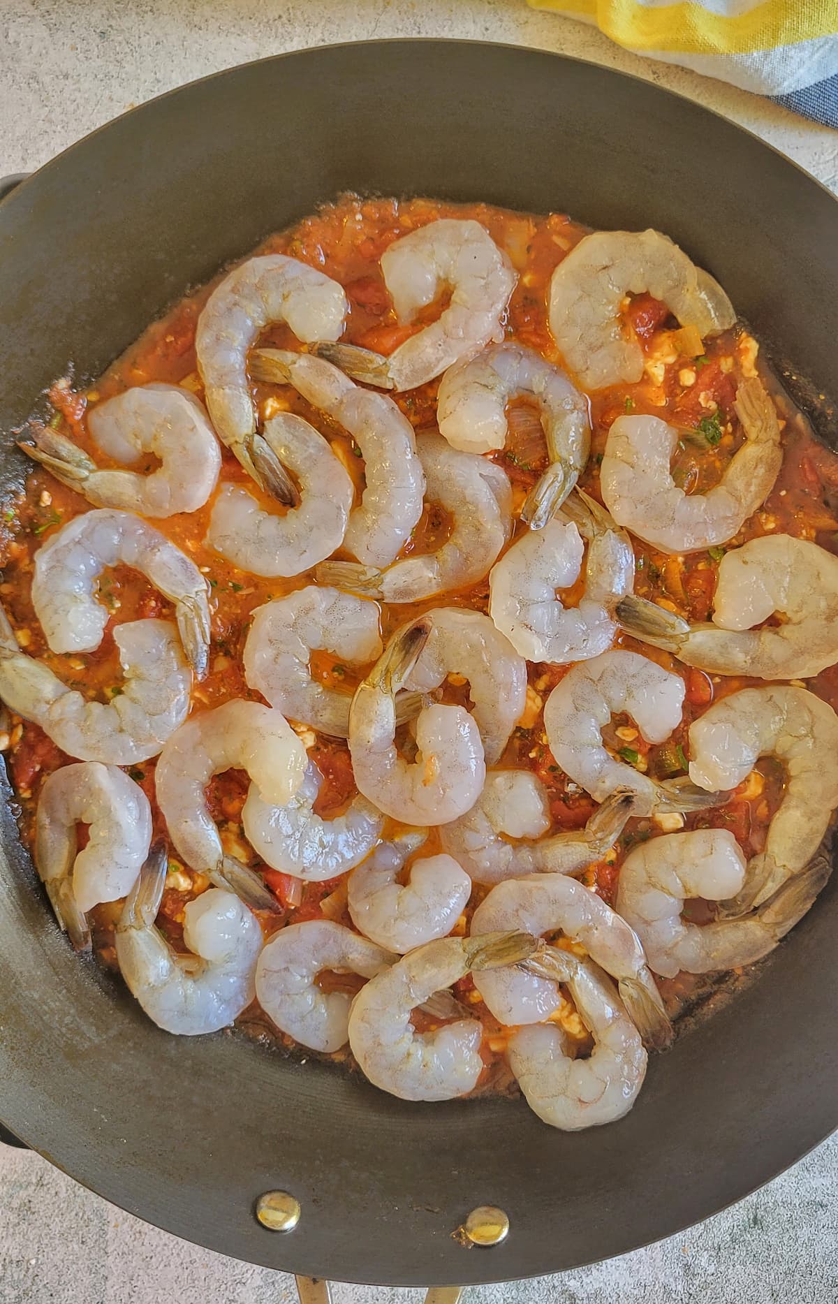 raw shrimp on a bed of diced tomatoes in a wok
