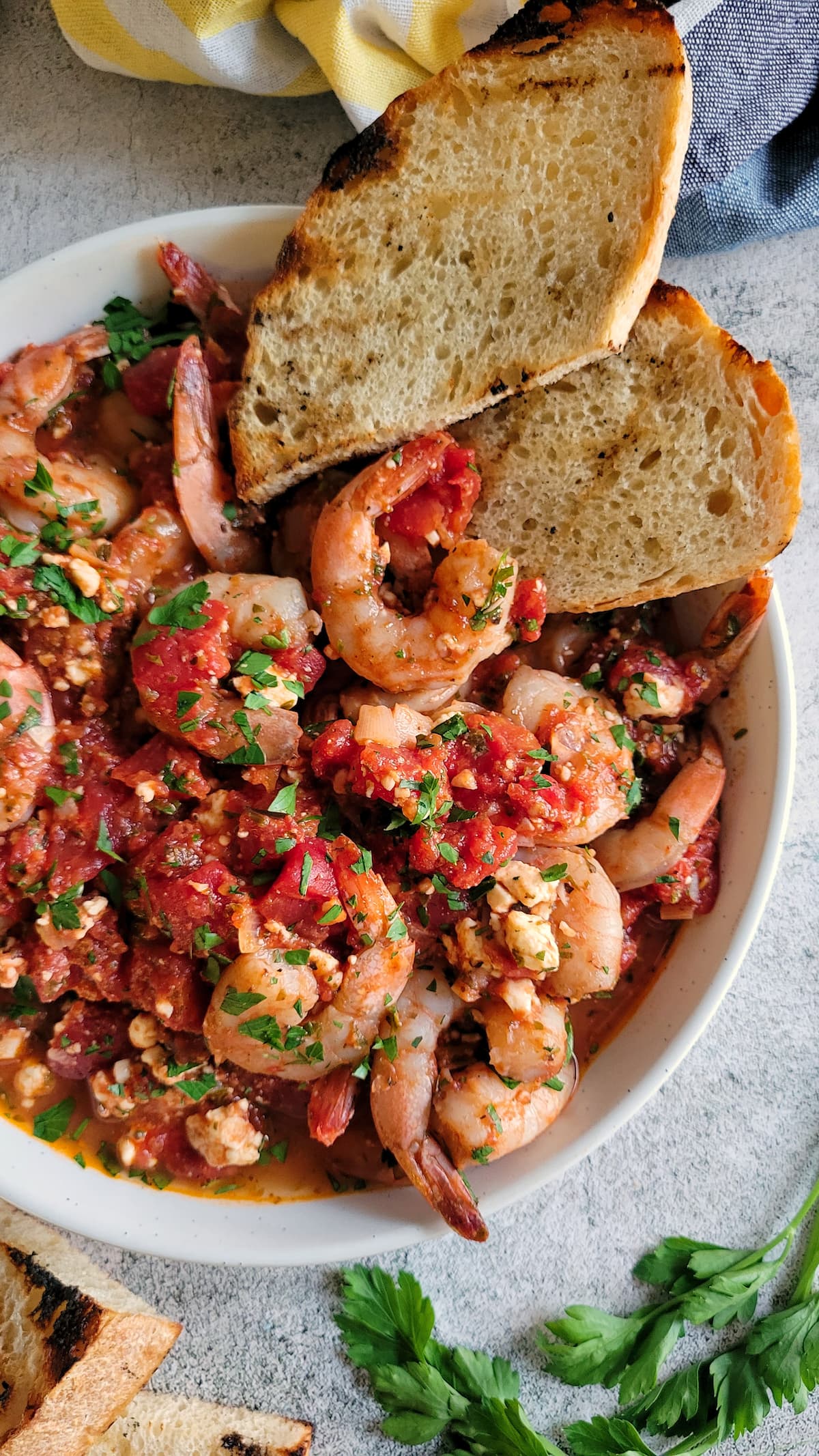 bowl of shrimp with fresh herbs and tomato sauce and two slices of bread