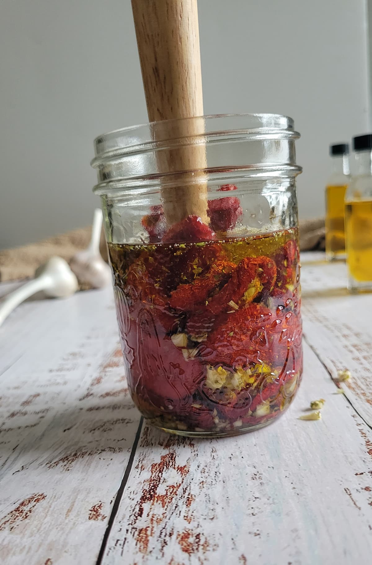 long wooden object in a jar with sun dried tomatoes, garlic and oil
