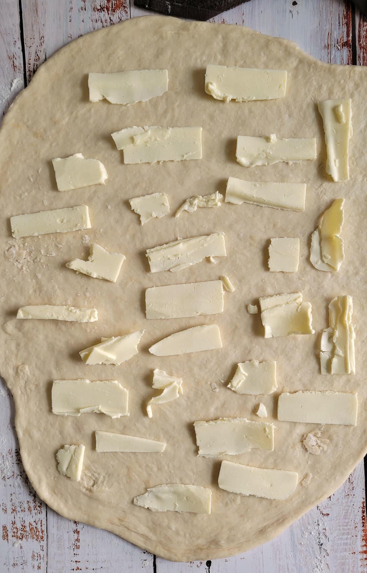 pieces of butter on a raw rectangular piece of dough