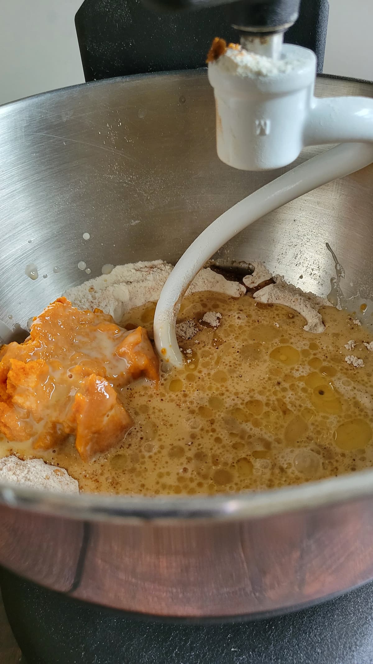 pumpkin puree in a mixing bowl with other ingredients and a dough hook