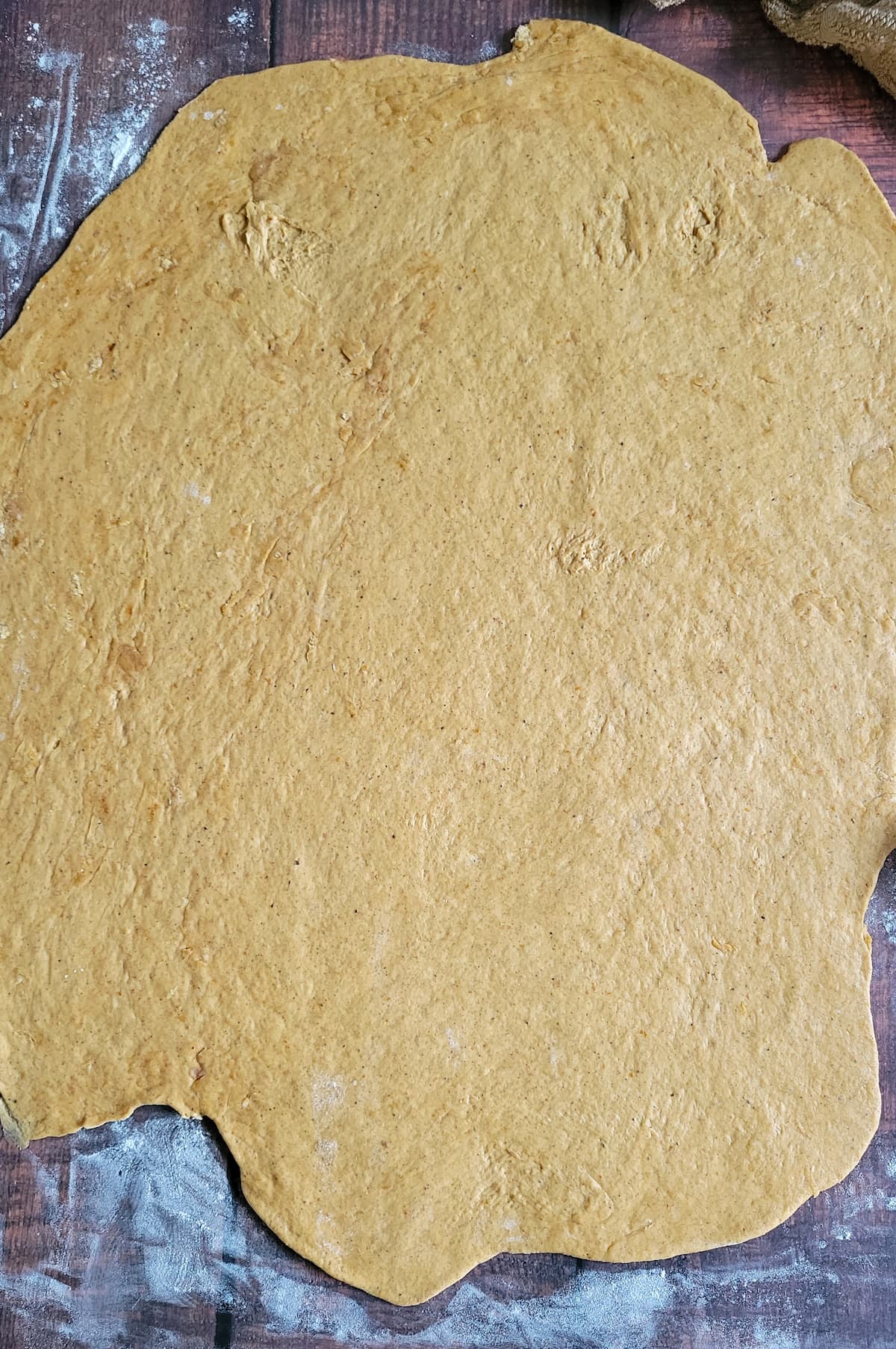 orange dough rolled out into a rectangular/circular shape