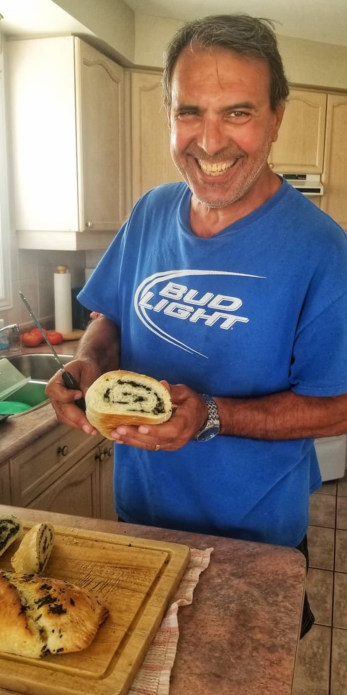 man with a huge smile on his face holding a freshly baked swiss chard roll