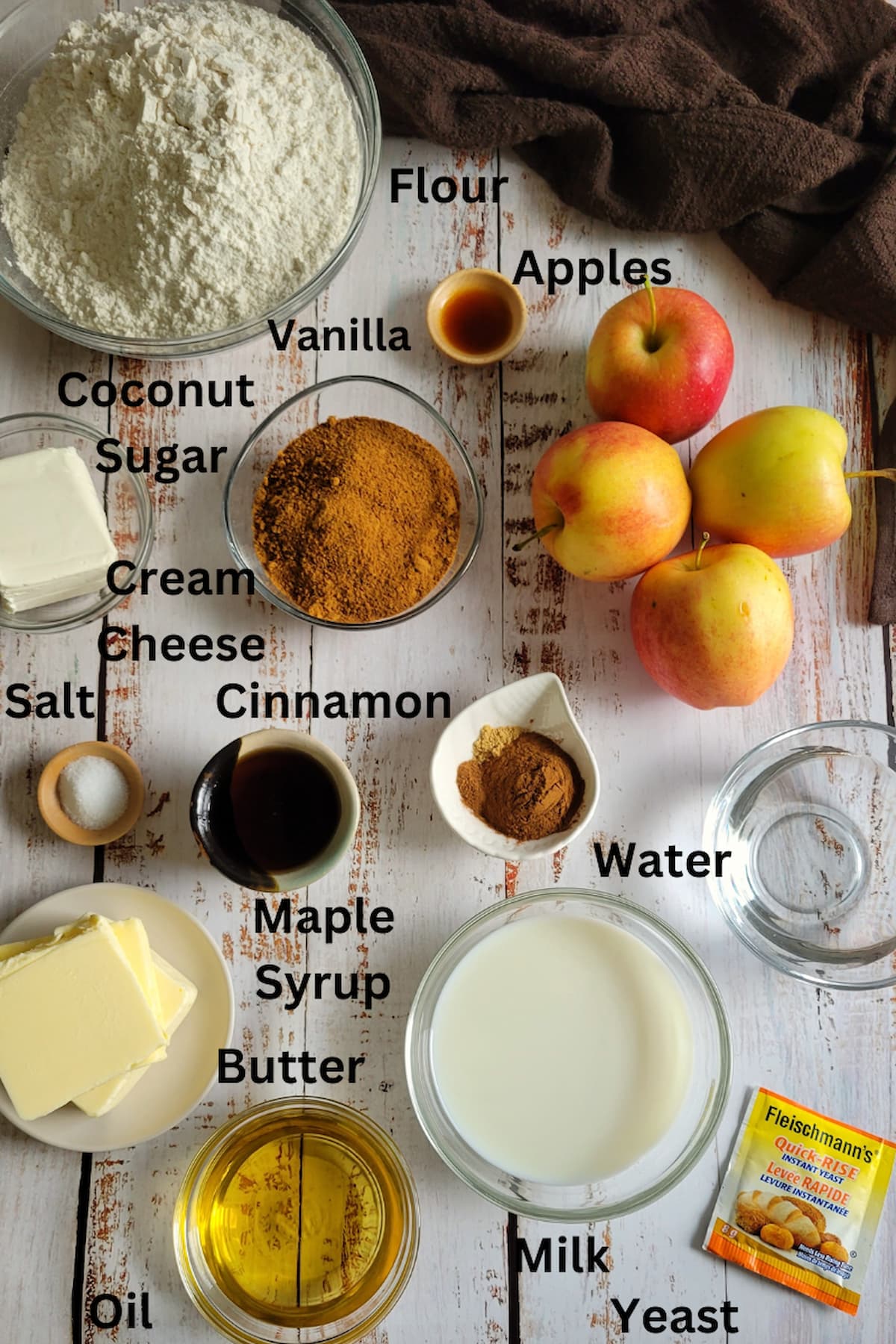 ingredients for cinnamon and apple rolls - apples, vanilla, flour, coconut sugar, milk, butter, cinnamon, yeast, eater, oil, maple syrup, salt, cream cheese