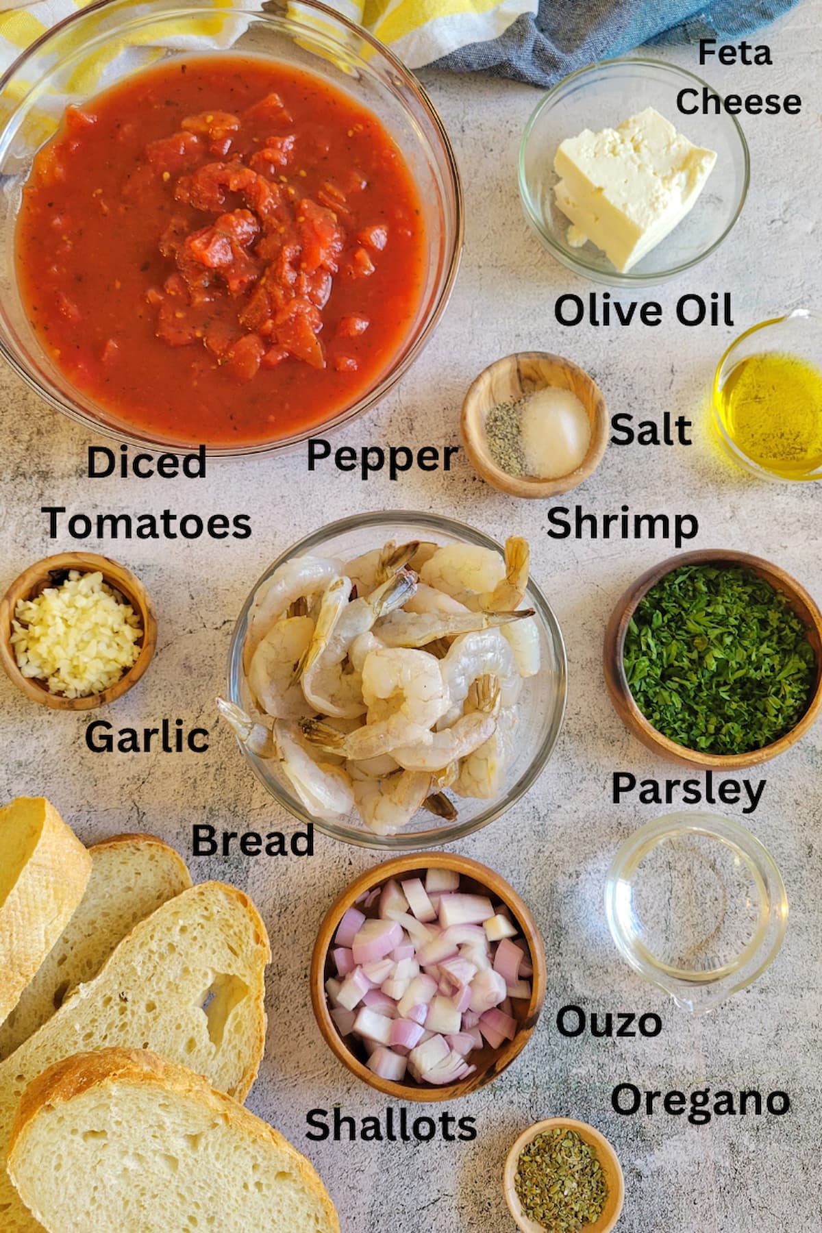 ingredients for recipe for shrimp bake - shrimp, feta, diced tomatoes, olive oil, garlic, parsley, salt, pepper, bread, oregano, ouzo, shallots