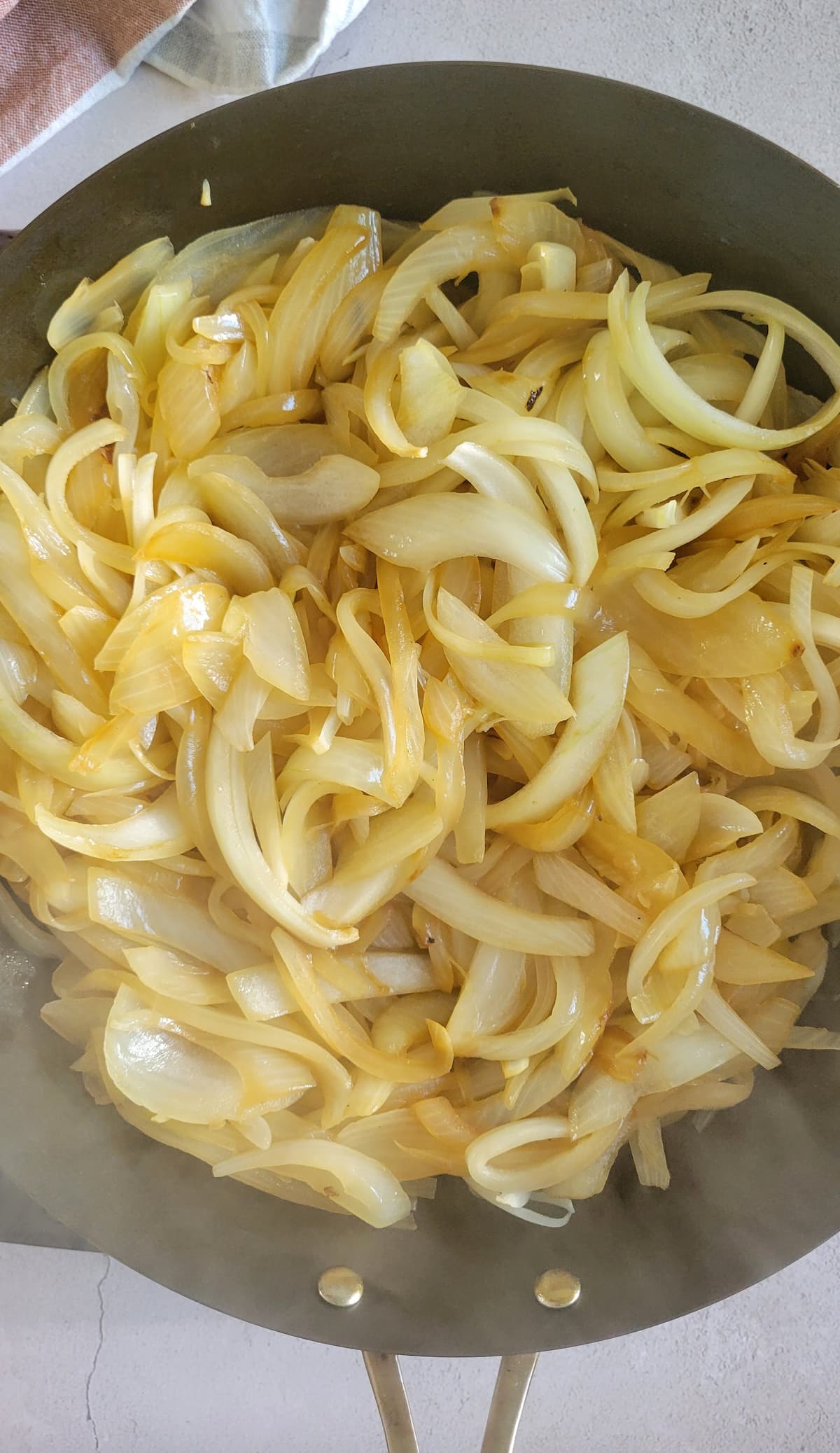sliced white onions cooking in a skillet