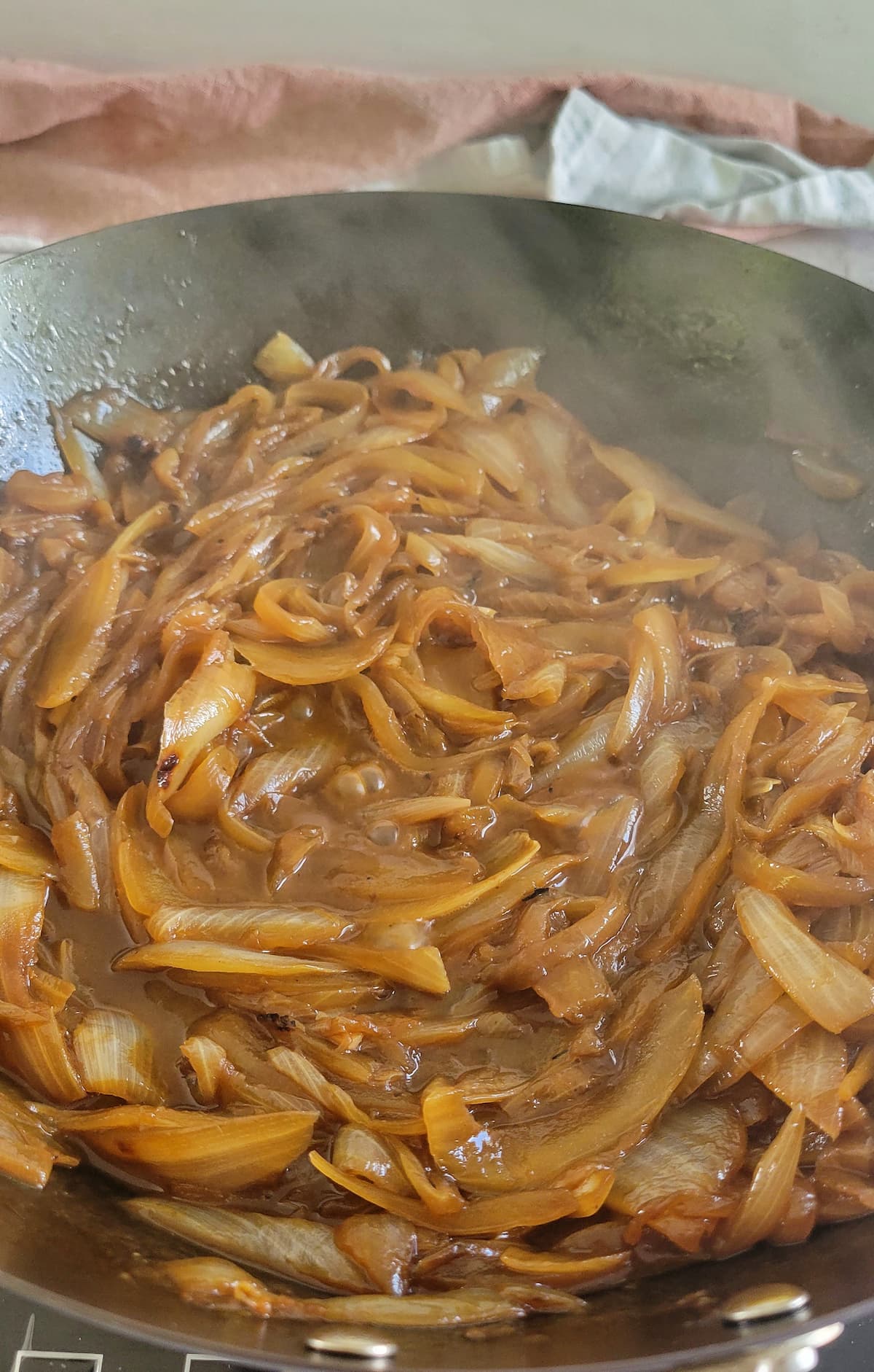 sliced onions caramelising in a skillet