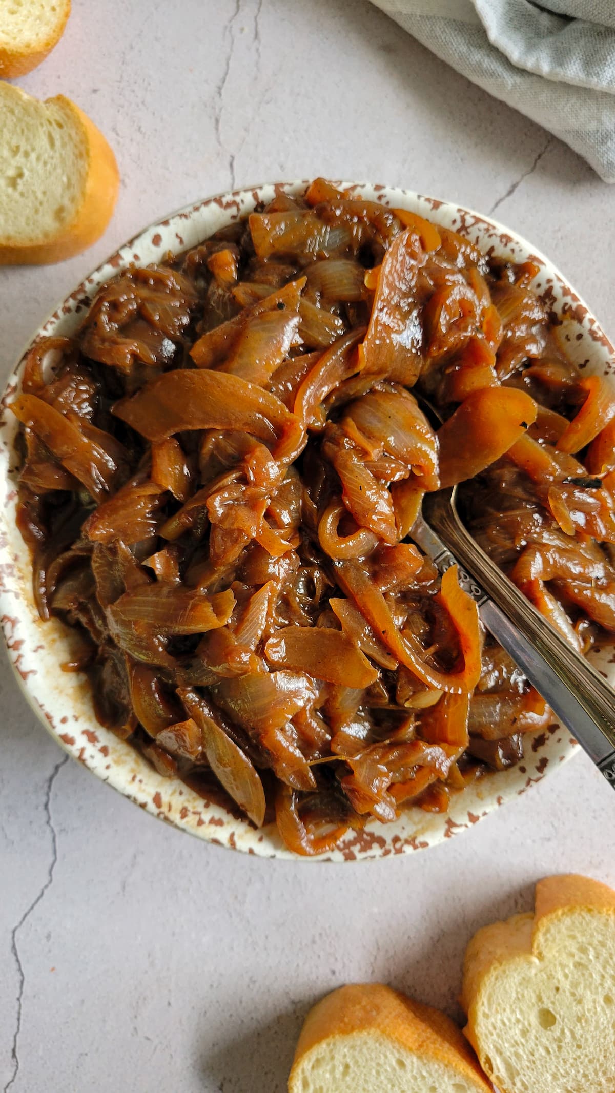 bowl of caramelised onions with a spoon in it, sliced bread on the side