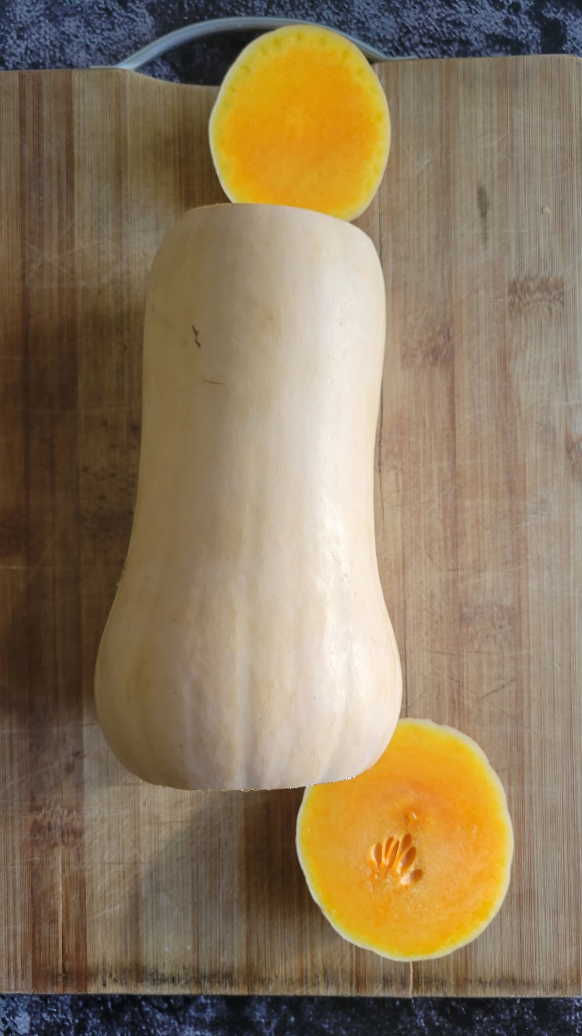 butternut squash on a cutting board with the two ends sliced off
