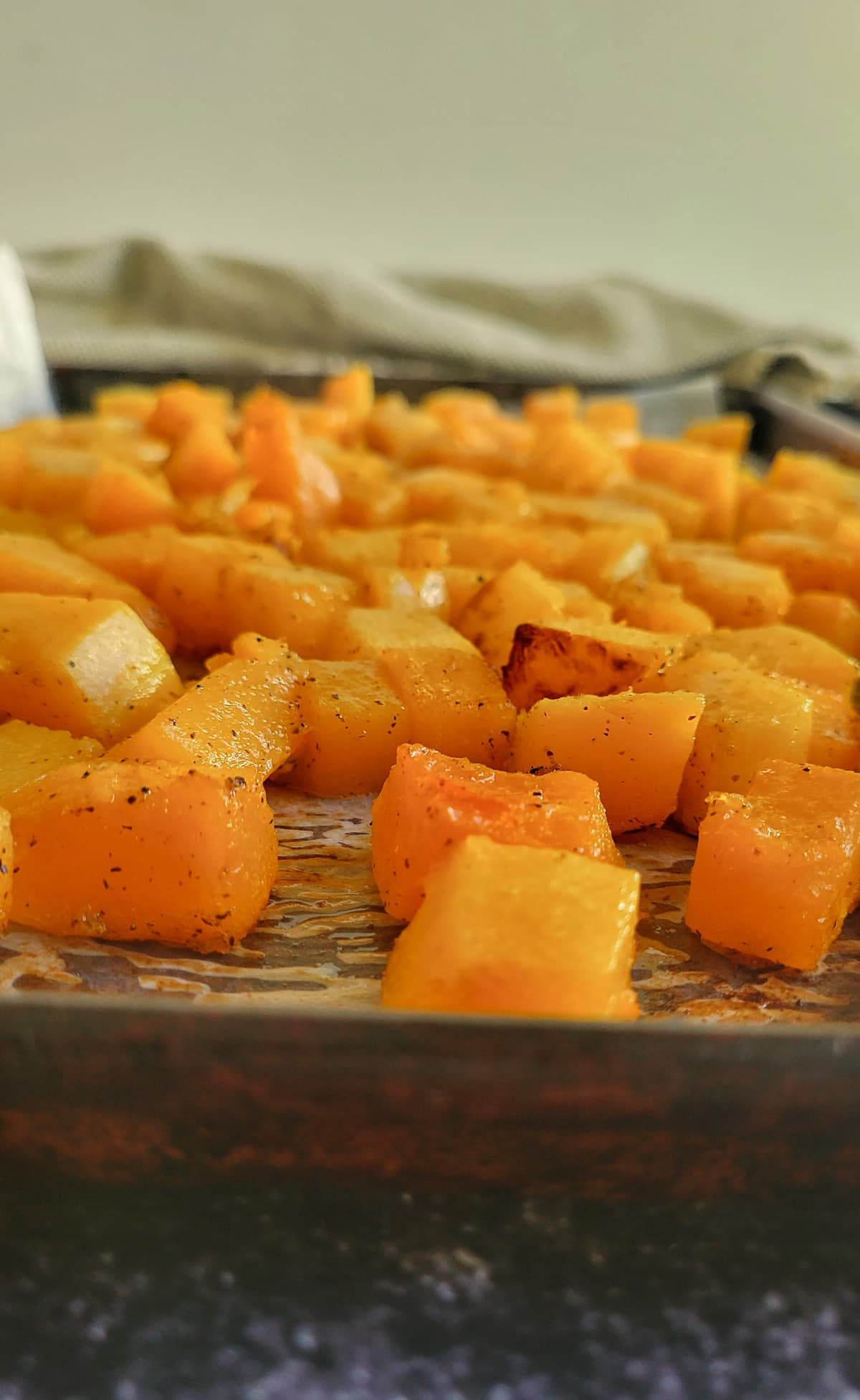 roasted butternut squash cubes on a parchment lined baking sheet