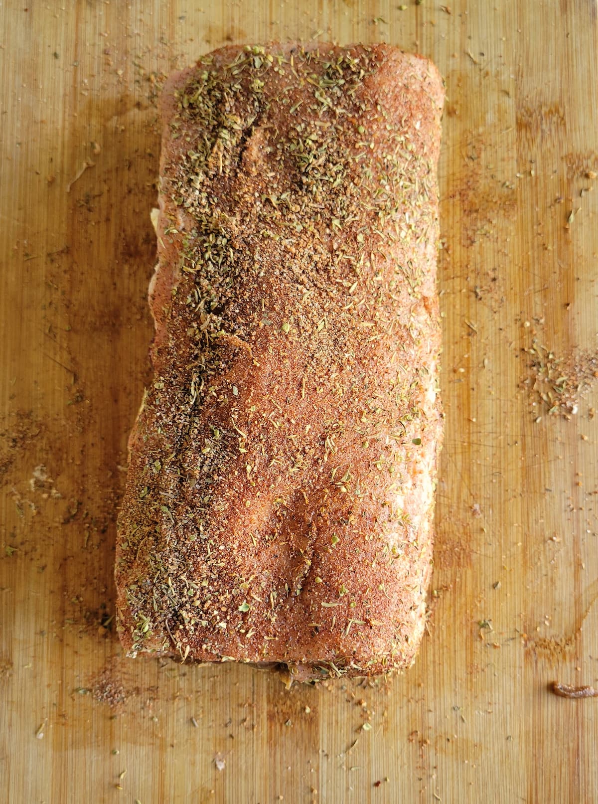 raw seasoned pork tenderloin roast on a cutting board