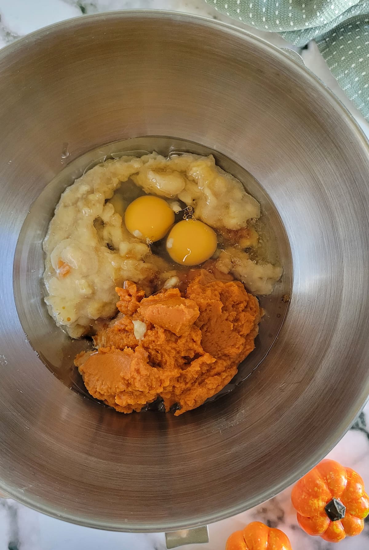 eggs, mashed bananas and pumpkin puree unmixed in a bowl