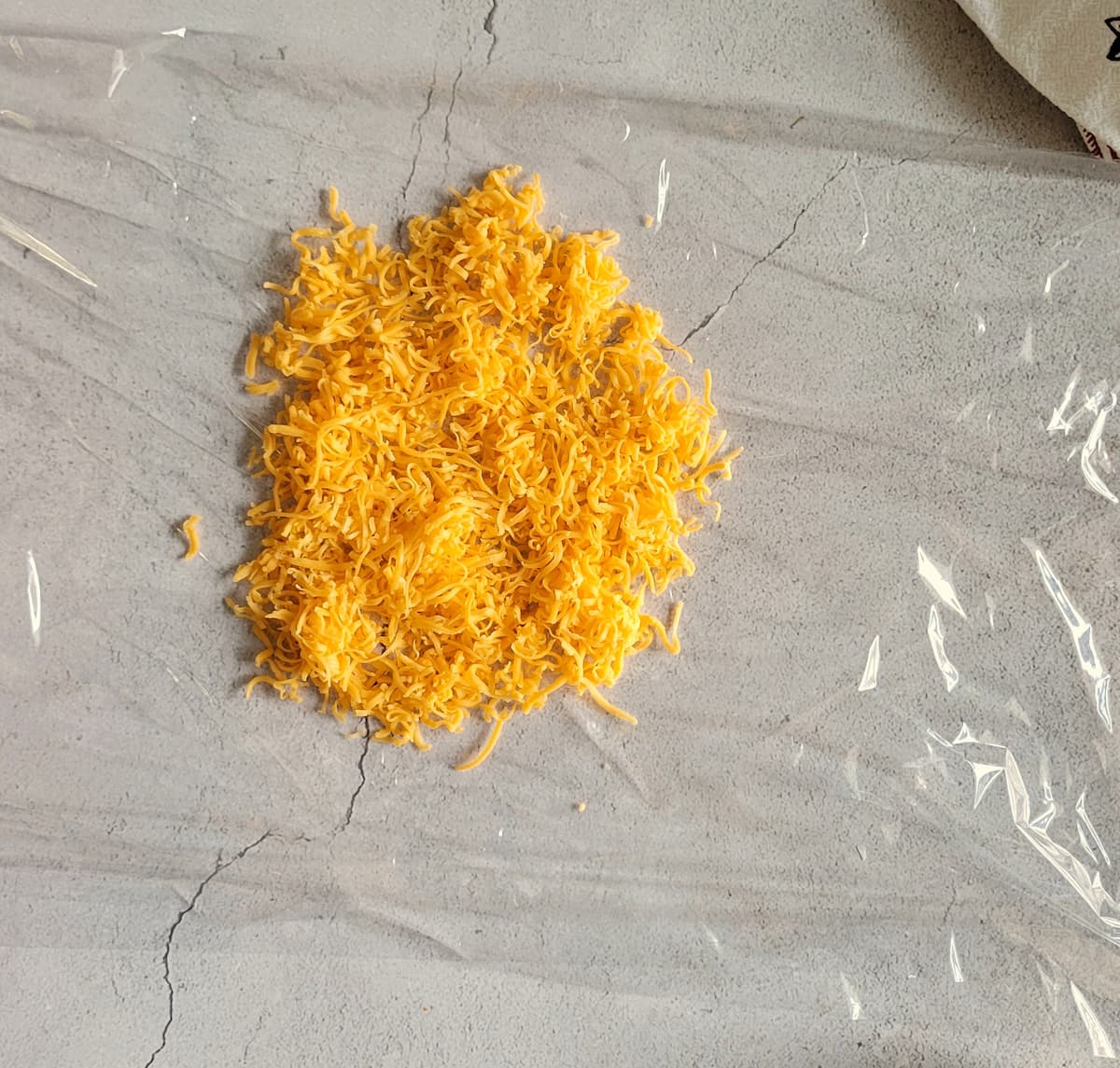 finely grated cheddar cheese on a piece of saran wrap