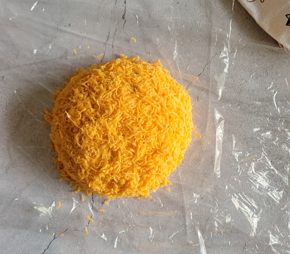 ball of finely shredded cheddar cheese on a layer of saran wrap