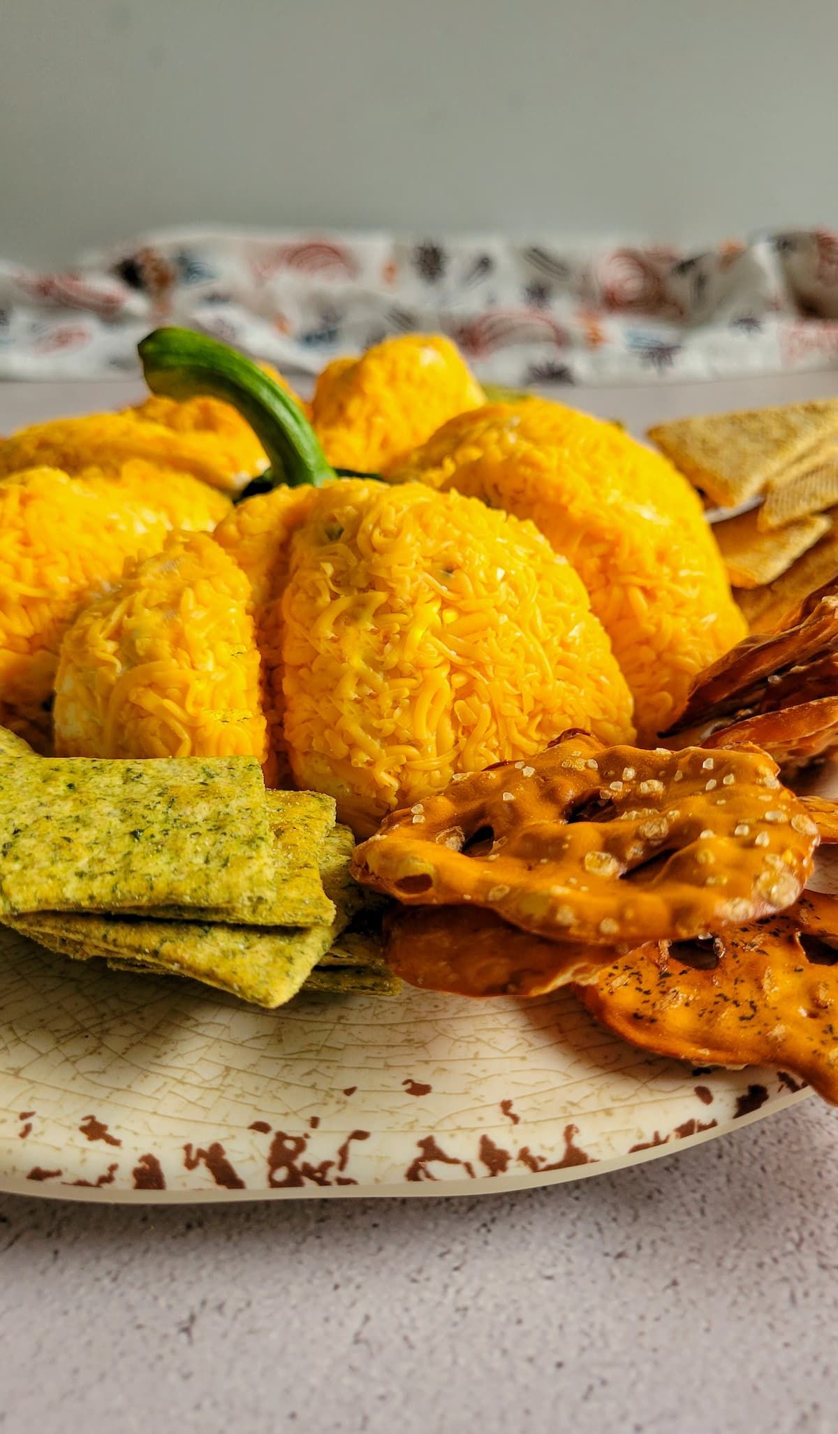 pumpkin shaped cheese ball on a plate with crackers