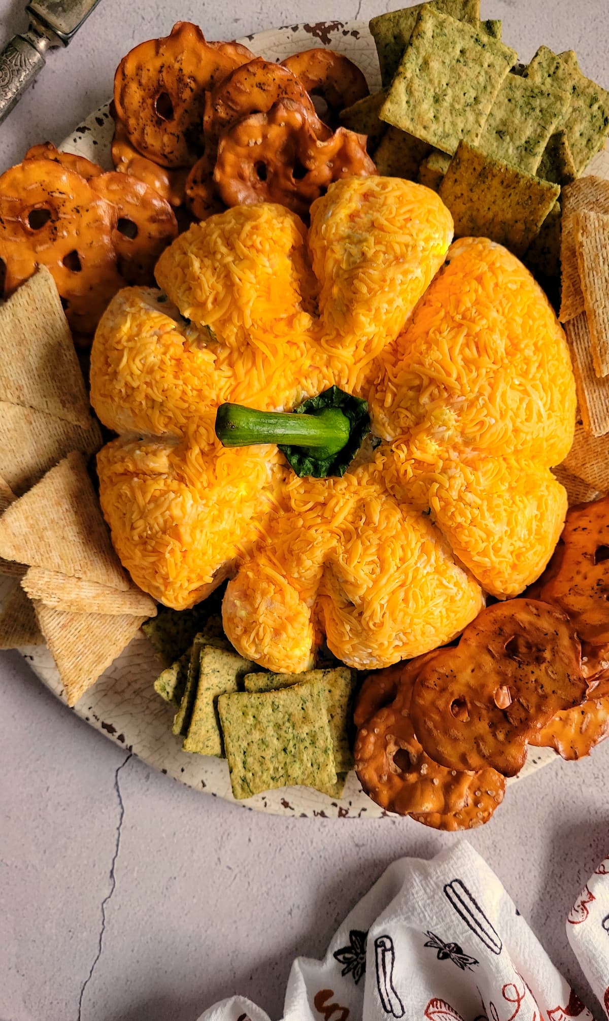 pumpkin shaped cheeseball with several different kinds of crackers on a plate