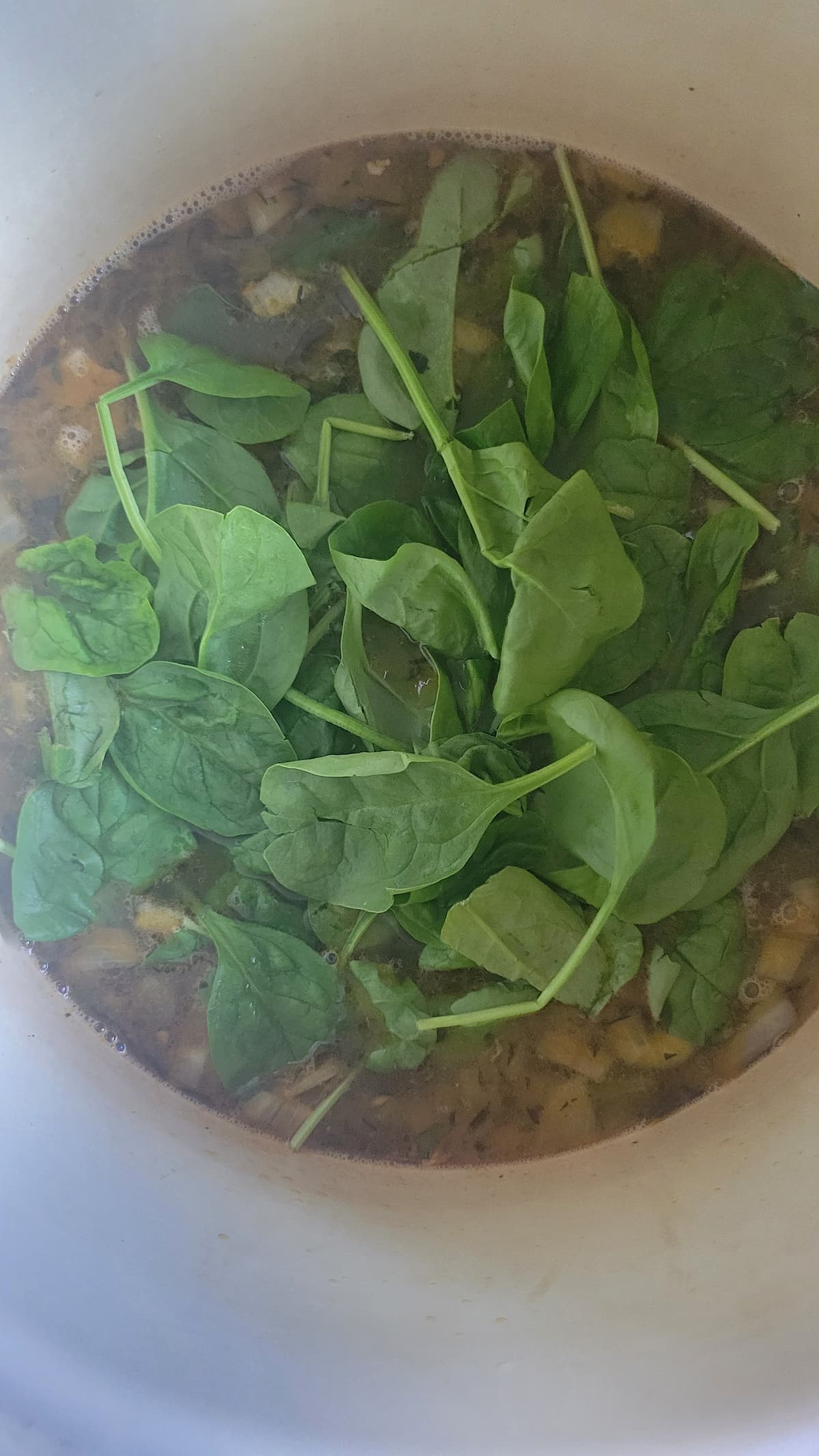 fresh spinach in a pot of soup