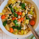 bowl of leftover turkey soup with pasta and veggies, more soup and turkey in the background