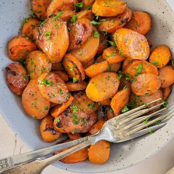 sliced glazed carrots garnished with fresh chopped parsley in a bowl