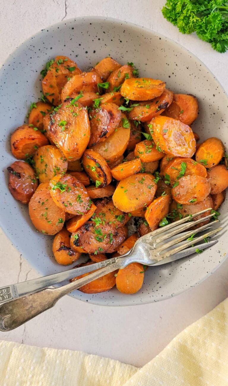 sliced glazed carrots garnished with fresh chopped parsley in a bowl