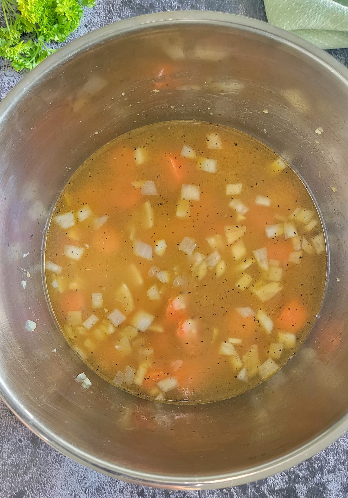 diced onions and carrot chunks in broth in a pot