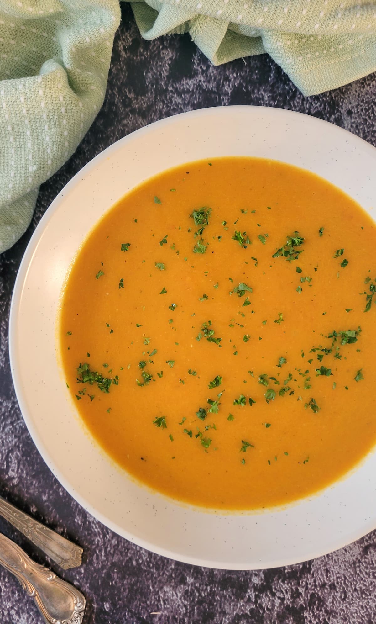 bowl of carrot soup garnished with chopped fresh parsley