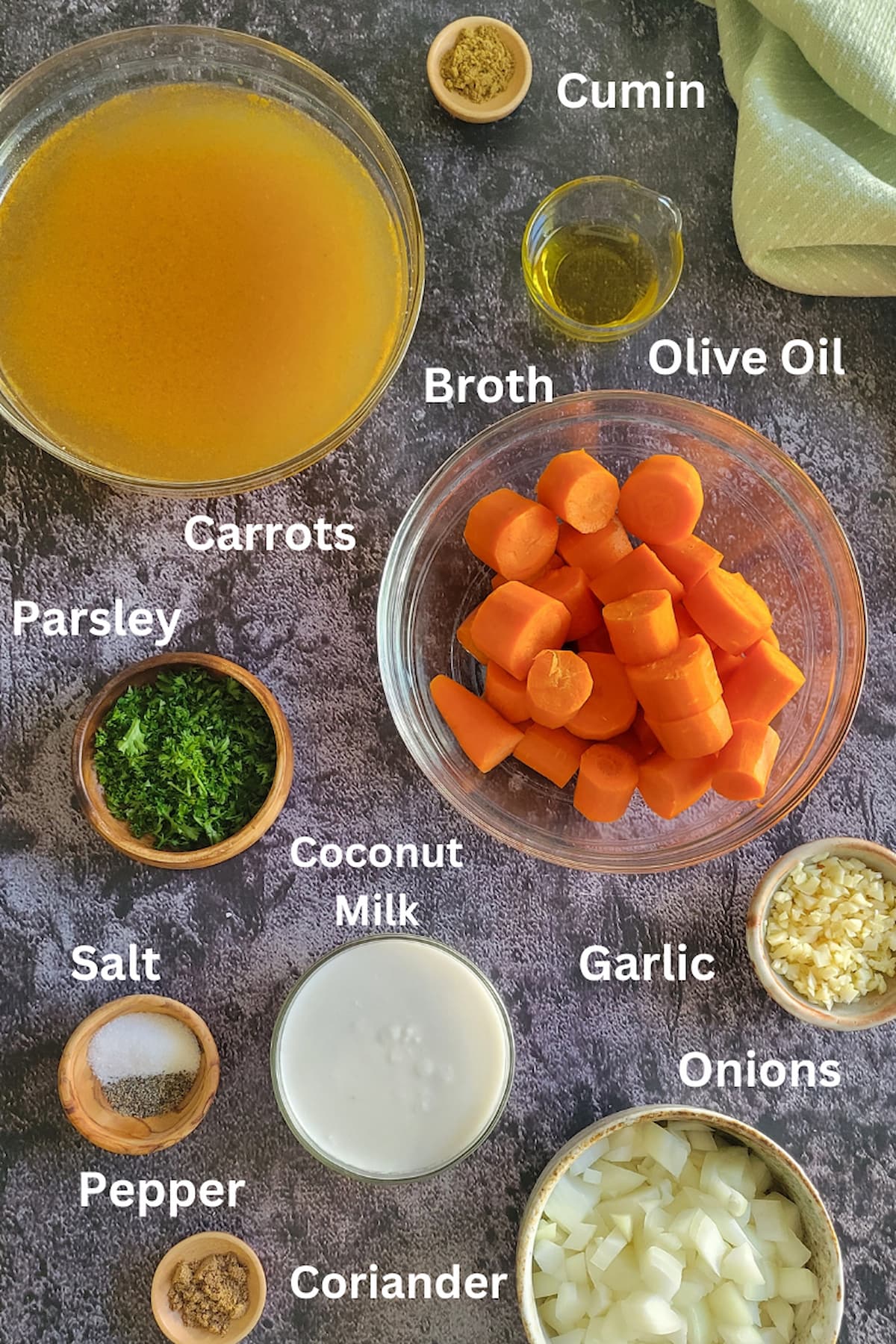 ingredients for soup with carrots - carrots, parsley, onions, garlic, salt, pepper, olive oil, cumin, coriander, coconut milk, broth
