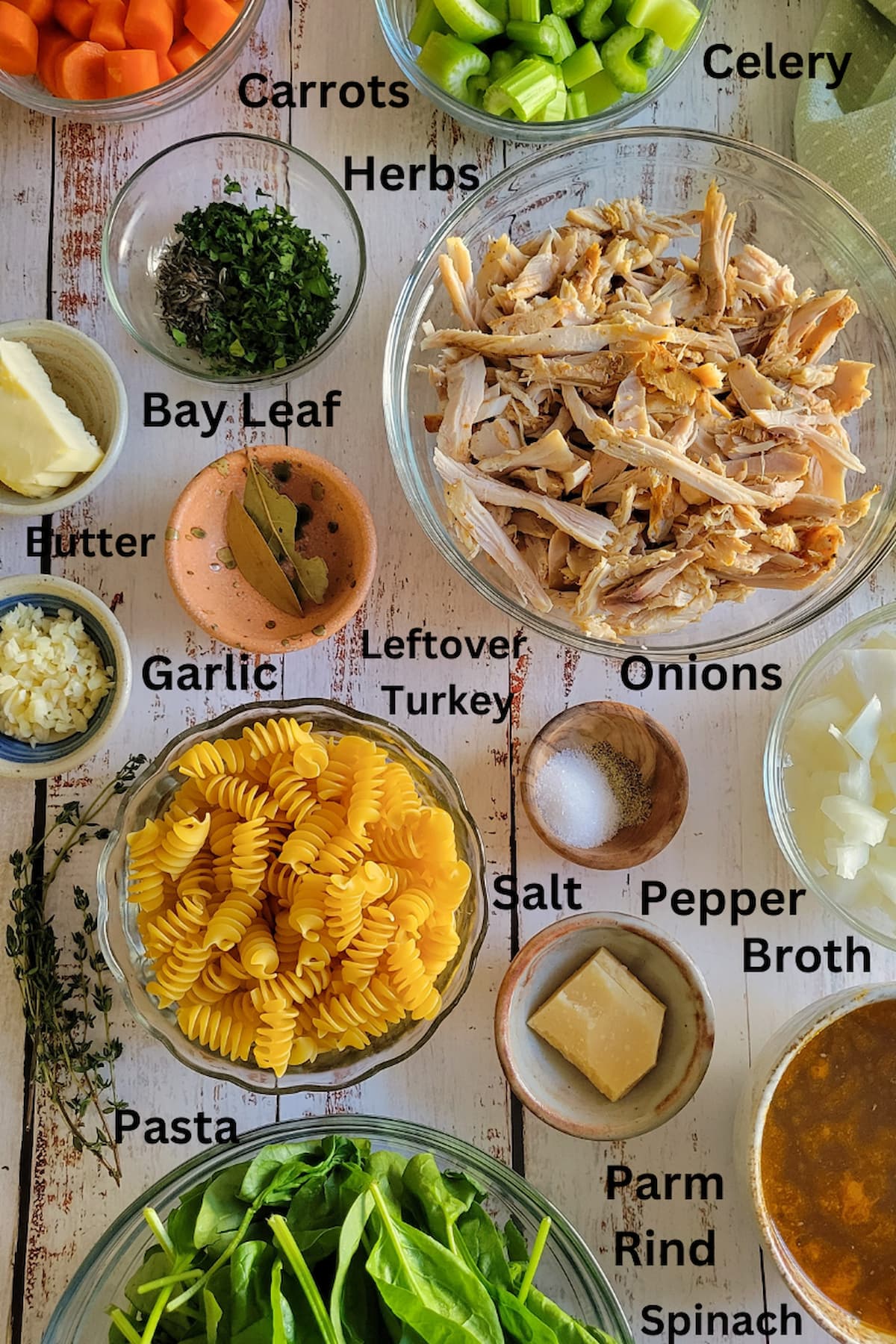 ingredients for leftover turkey turkey soup - leftover turkey, carrots, celery, onios, garlic, herbs, spinach, parm rind, broth, salt, pepper, pasta, butter, bay leaf