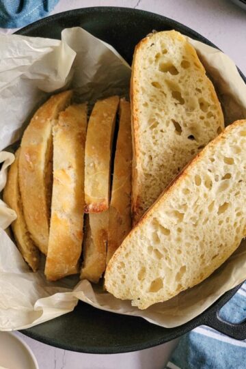sliced bread in a parchment lined dutch oven, jam and butter on the side