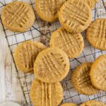 peanut butter cookies on a wire rack, glass of milk in the background