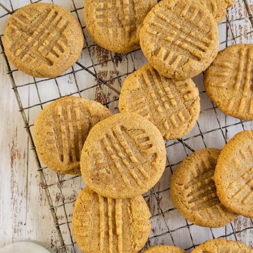 peanut butter cookies on a wire rack, glass of milk in the background