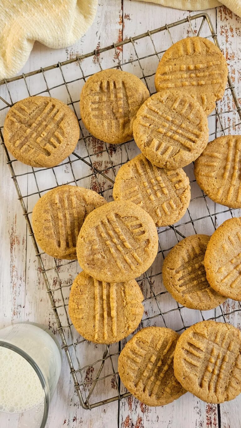 peanut butter cookies on a wire rack, glass of milk in the background